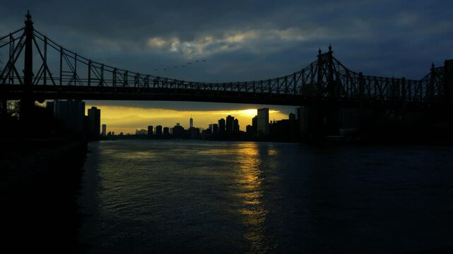 Birds passing as the sun is setting under the queensbridge in Queens, NY