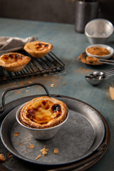Golden-brown Portuguese custard tart on a rustic metal tray