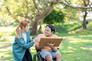 Disabled artist engaging with instructor while working on art outdoors in a sunny park