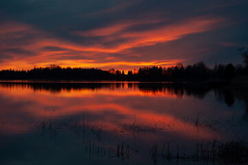 Fototapeta premium Sunset colours reflected from a calm lake in spring in Western Finland