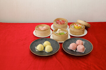 Assorted dim sum and dumplings are presented on plates, showcasing colorful fillings, set against a...