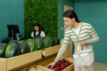 Fototapeta premium Asian woman shopping in local fruit store wearing green cardigan selecting fresh fruits from wooden shelves. Vibrant shop interior with tropical produce and customer-focused business.