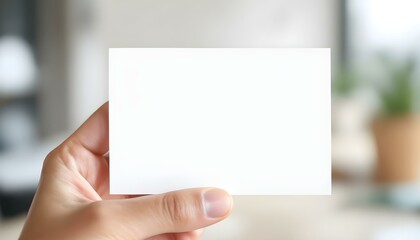 A hand holding a blank white card, close-up focus, with a blurred professional background, creating a clean and minimalistic look.