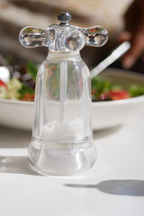An adorable glass salt shaker placed elegantly on a dining table