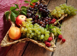 Grape. A basket of ripe fruits on a wooden table. A treat. Sweet dessert. Food. Juicy berries. Beautiful fruit background. Vitamins. Harvest. Blue and green grapes. Season. still life 