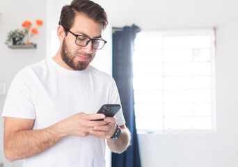 Joven apuesto con el celular en mano escribiendo un mensaje de texto