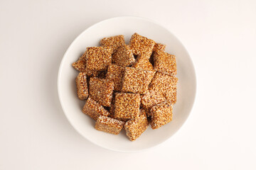Sesame seed jaggery chikki or til ke chkki and tilgul or til gul ladduchikki served in bowl for Makar Sankranti Festival in India