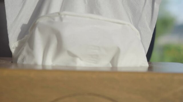  hand pull out a piece of tissue from tissue paper box 