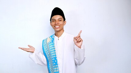 handsome asian muslim young man smiling pose pointing up and open palm for promotion, product and discount. recommend something with isolated white background