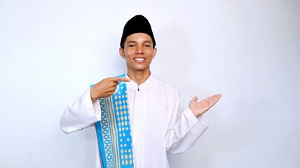 handsome asian muslim young man smiling pose pointing palm promotion, product and discount on the side. recommend something with isolated white background