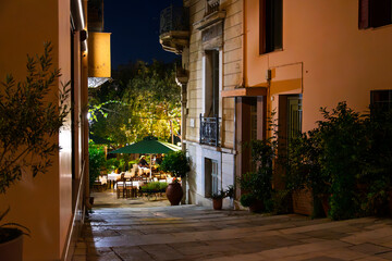 An illuminated sidewalk cafe late at night in the historic Plaka district of Athens, Greece. 