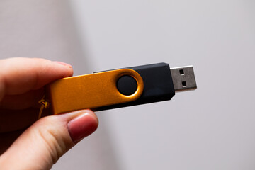 a woman's hand holding a gold yellow usb 