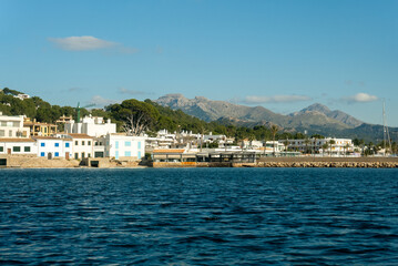 A line of boats docked in Port d'Andratx, Mallorca, with white houses along the harbor and...