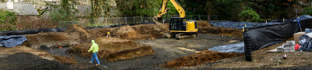 New home construction foundation earthwork, surveyor with laser level range finder, heavy equipment...