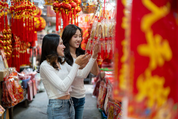 Obraz premium Young Asian Women Shopping for Traditional Offerings Outdoors