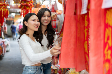 Fototapeta premium Young Asian Women Shopping for Traditional Offerings Outdoors