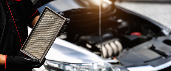 Car care maintenance servicing technician or auto mechanic holding car air conditioner filter for...
