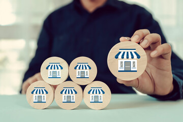 Hand choose wooden toy stack with franchise icon for goal to growth is investment planning...