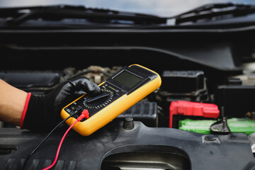Electrical technician car mechanic use voltmeter to check voltage battery low energy problem for car care service maintenance and re charger or jump start or change battery replacement.