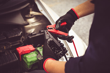 Electrical technician car mechanic holding booster cables for jump start car for empty battery dead...