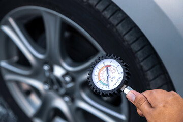 Hand car mechanic holding car tire pressure check equipment tool to checking low tire pressure...