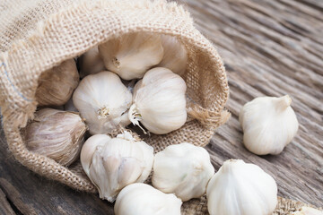 Garlic with sack on old wooden table background