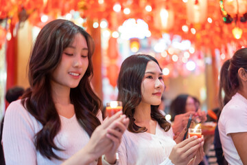 Two young Women praying with red candle in Chinese temple