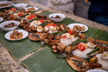 Deliciously arranged variety of dishes served on banana leaves at a festive gathering in the evening