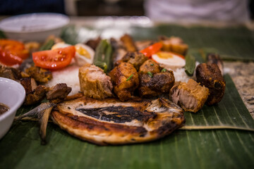 Delicious traditional meal served on banana leaves with grilled meats, rice, and vegetables at a festive gathering