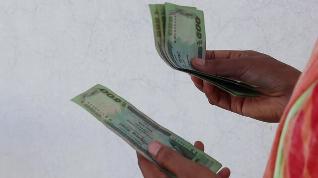 A close-up of a woman's hand counting Bangladesh 500 Taka banknotes. Five hundred Taka (BDT).