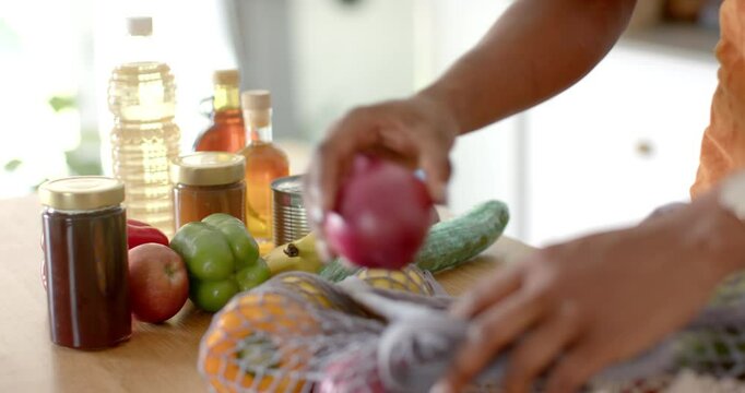 Arranging groceries on kitchen counter, person organizing fresh produce and jars