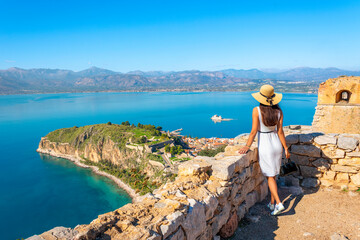 A young female tourist overlooks the Akronafplia Fortress and Palamidi Island from the Fortress of Palamidi at Nafplio, Greece.