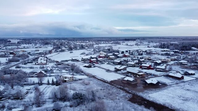 Aerial shot of the snow covered landscape, countryside of Katlakalns, Riga on a cold winter day, cloudy sky, copy space
