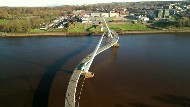 Aerial shot of the Peace Bridge in Derry-Londonderry, NI. The camera reverses over the bridge to reveal Derry City and the Guildhall. Filmed in 4K at 60fps and in Rec709 color space.
