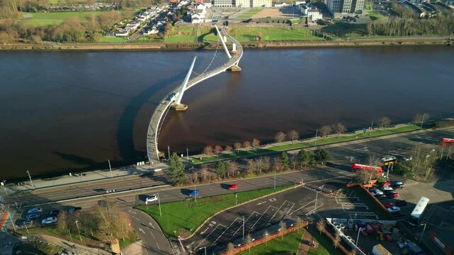 High and wide aerial shot of the Peace Bridge, River Foyle, Ebrington Square and the Guildhall in Derry-Londonderry, NI. Filmed in 4K at 60fps and in Rec709 color space.