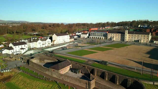 Aerial shot of Ebrington Square in Derry-Londonderry, NI on a bright and sunny day. The camera advances over the park and onto the square. Filmed in 4K at 60fps and in Rec709 color space.