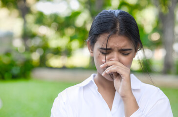 Allergic sick South Asian or Indian woman having runny nose, nose stiffness, stiff nose with snot, nasal mucus due to cold or flu, air dust pollution allergy, health care and allergy concept image