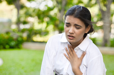 Unwell, ill and sick South Asian Indian woman panting, suffering with acid reflux or gerd symptoms, acidic esophageal, heartburn, asthma sickness