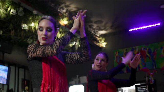 Flamenco dancers in Tablao, Spain. A Spanish flamenco dancers is wearing a black dress and red shawl, and they is dancing