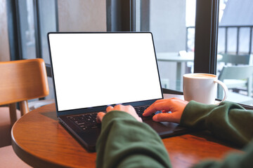 Mockup image of a woman working and typing on laptop computer with blank white desktop screen in cafe