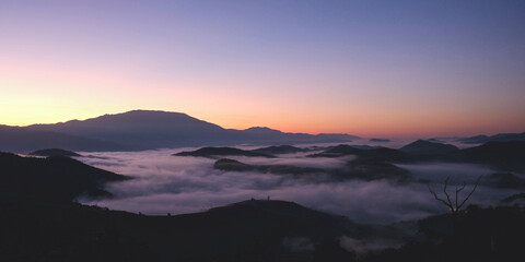 Landscape view of the sea of fog flowing on hills at dawn