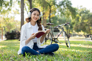 Young asian woman relaxing reading book sitting at public park life style outdoor. Happy female Take a break enjoy time living in the nature. Human and nature together