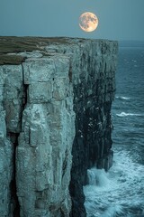 Majestic cliffs at sunset with rising moon and crashing waves on the coastline