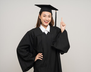 Happy asian woman in graduation costume with cap on isolated background. College degree successful...