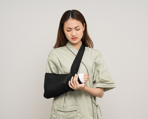 Depressed upset woman suffering from pain. Broken arm. Asian woman put on plaster bandage cast...