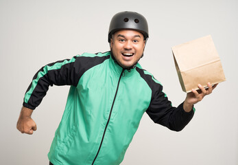 Young asian rider wearing green jacket uniform and bike helmet various action holding food paper bag delivery to customer. Male delivery service worker. Courier and shipping food service.