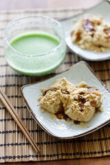Cup of fresh matcha tea and Warabi mochi, traditional Japanese sweet from bracken starch on wooden table.