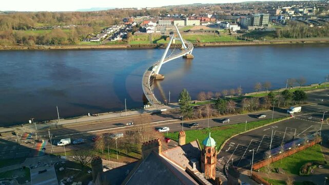 Forward travelling aerial shot of the Guildhall and Peace Bridge in Derry-Londonderry, NI. Filmed on a brigh sunny day. Produced in 4K at 60fps and in Rec709 color space.