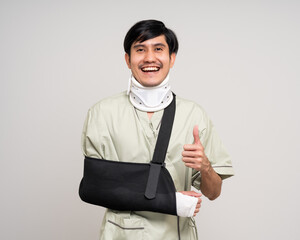 Happy young asian man broken arm on isolated background. Asian man put on plaster bandage cast...