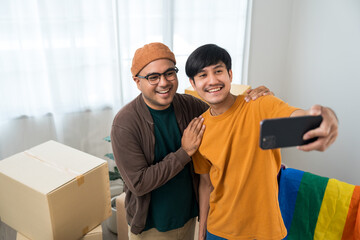 The LGBT couple asian family buying new house. Moving relocation with parcel box cardboard. They...